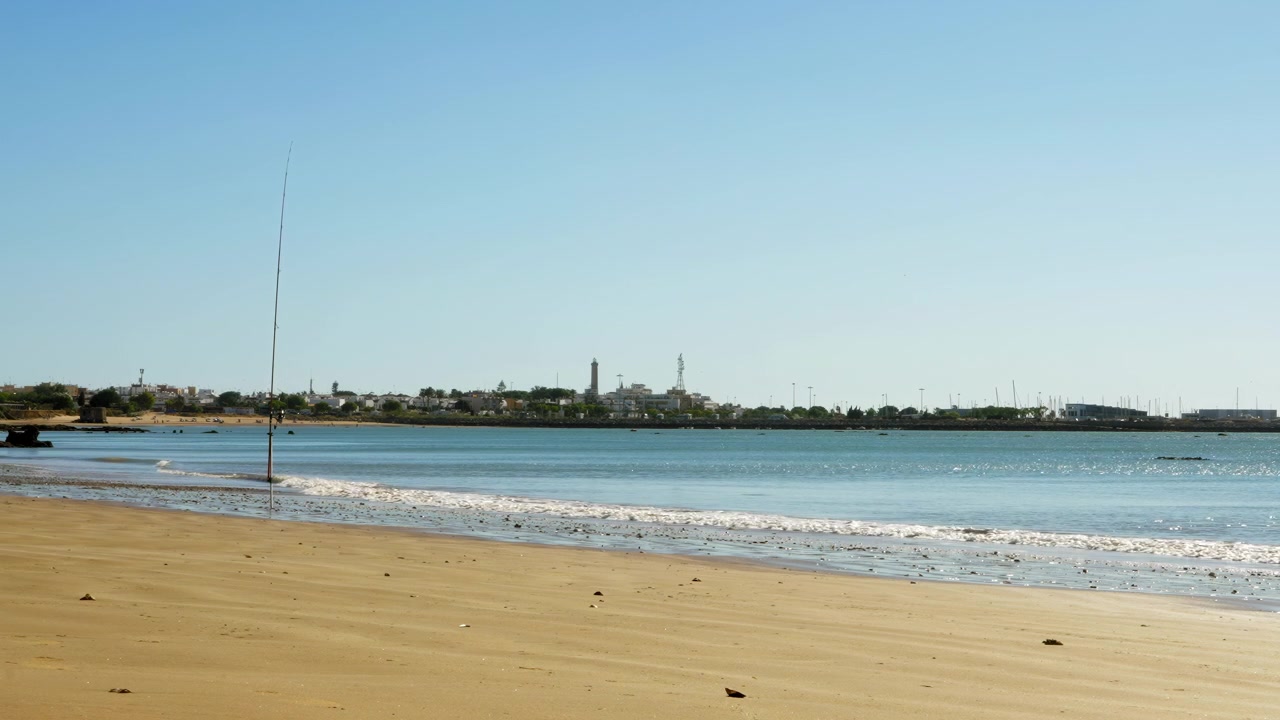 Pantai dekat Chipiona, Cadiz, Spanyol, dengan langit biru cerah.