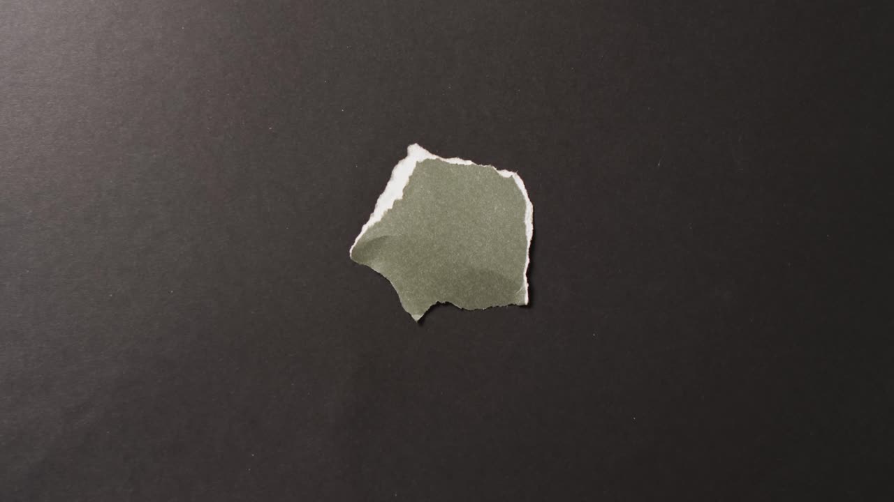 video de primer plano de un pedazo de papel verde roto sobre un fondo negro