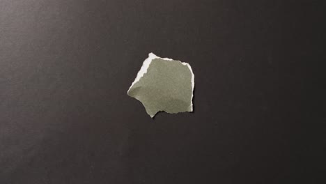 video of close up of torn piece of green paper on black background