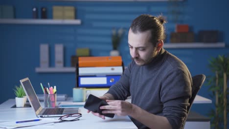 Accounting-man-looking-at-his-empty-wallet-at-home.