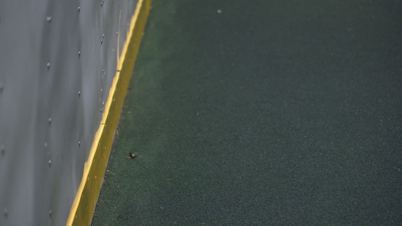 movimiento dinámico de una pelota de fútbol rebotando contra una pared metálica con un borde amarillo vibrante, creando movimiento e impacto, la escena captura el tiempo preciso