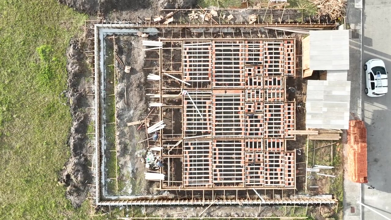 Aerial view of modern residential houses under construction using precast concrete elements with workers on site in Brazil.