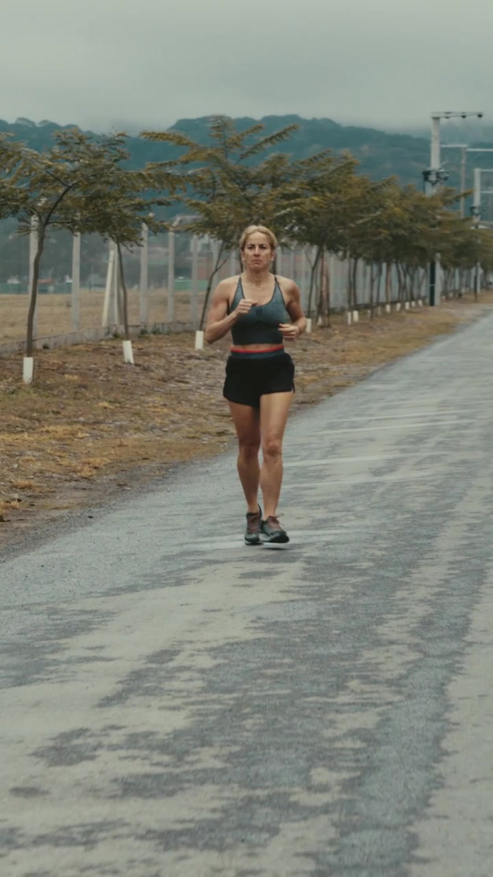 Mulher em forma correndo em uma estrada tranquila em um dia nublado