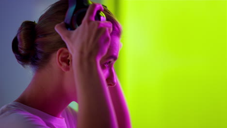 cyber gamer putting headset in neon room closeup. esport professional preparing