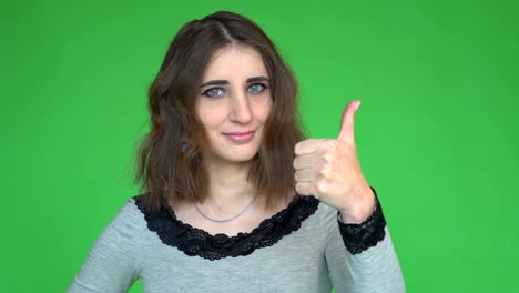 Young woman showing thumb up. Posing against a removable chroma key background.