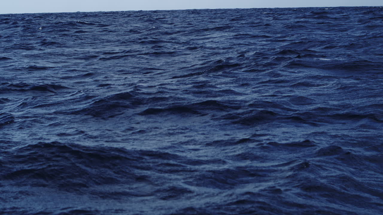 Onde oceaniche più scure si alzano e si abbassano con picchi più pronunciati sotto una luce diurna più fioca