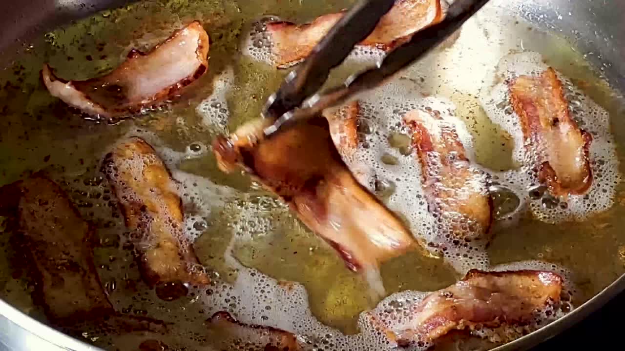 Close-Up Of A Slices Of Bacon Being Flipped On Stovetop