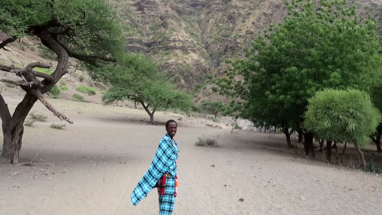 Guida africana locale in abito tradizionale posa davanti a una montagna durante un'escursione di arrampicata