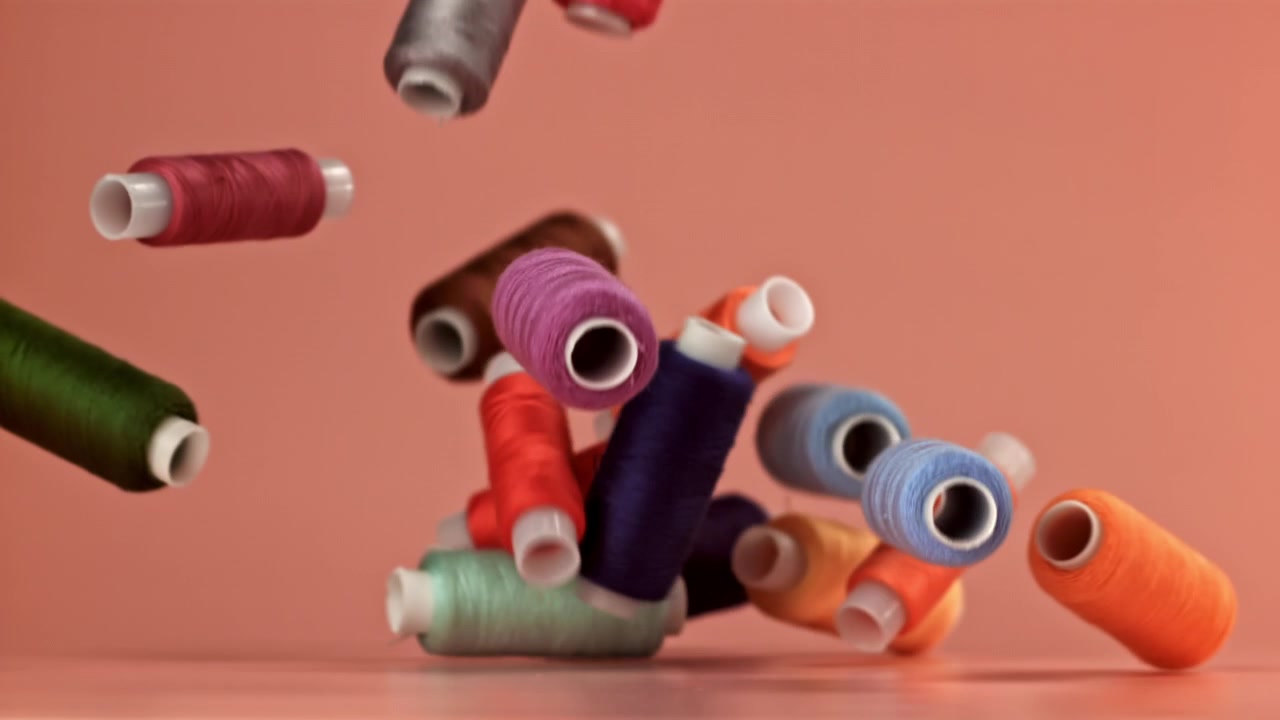 Colorful Spools of Sewing Thread Falling in Slow Motion