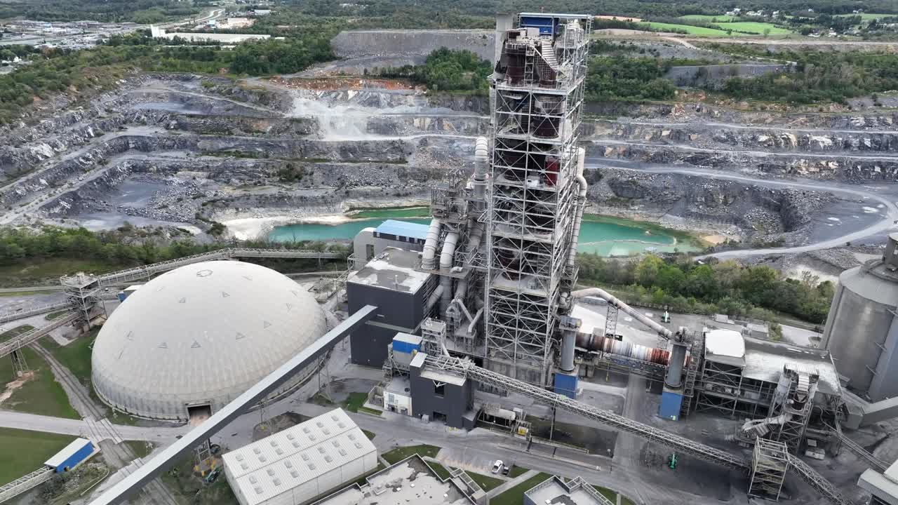 Aerial view of industrial cement plant in martinsburg, with tower and lake in background. Industrial zone with quarry in USA. Flyover shot