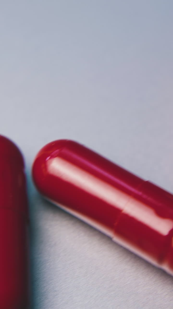 motion along row of bright red medical capsules lying on clean white background extreme close view