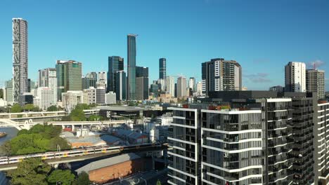 aerial drone shot of brisbane cityscape from west end, camera passes close to an apartment building with rooftop pool