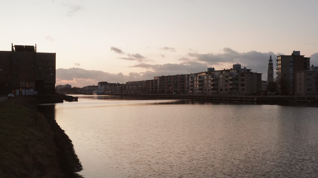 Drone shot of a canal in a city with offices and residential buildings during sunset