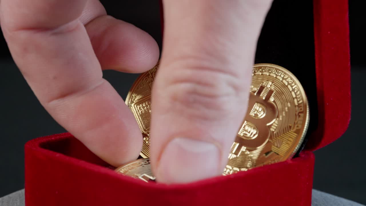 caja de joyas con bitcoins físicos gira en la mesa giratoria como la mano entra para recoger y quitar una moneda