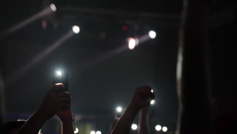 hands raised in celebration at a lively concert with bright lights and energetic atmosphere