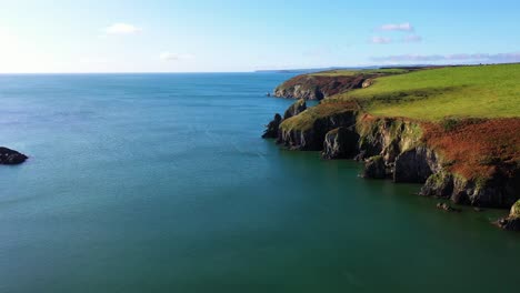 Aerial-flying-over-costal-cliffs-during-sunny-day,-pedestal-movement