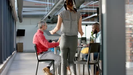 team of diverse colleagues discussing while sitting on a table together at office