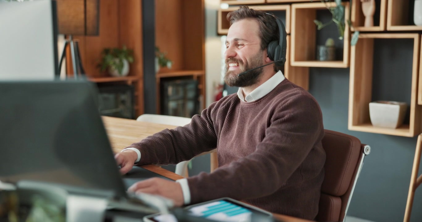 Professionel mand med headset deltager i videoopkald på et moderne kontor