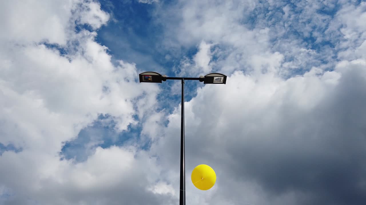 노란색 부풀어올릴 수 있는 풍선이 야외에서 거리 등불을 돌아다니고 있습니다.