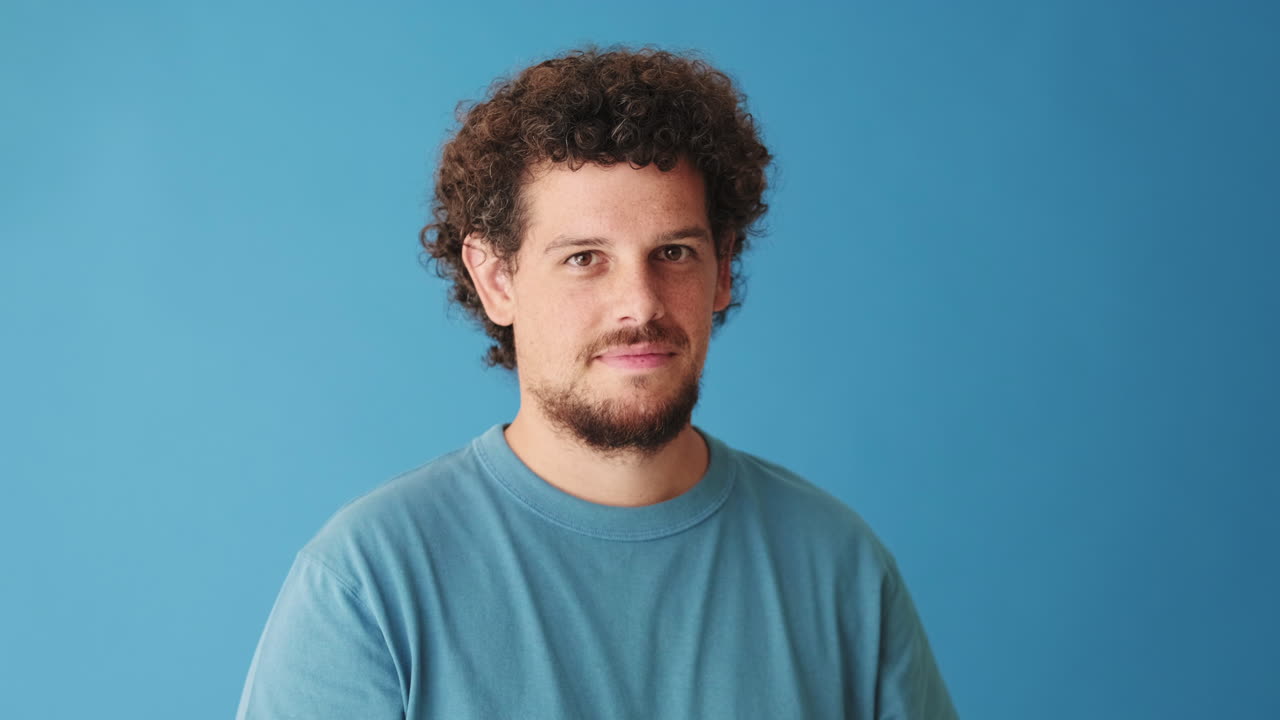 Confident Young Man with Curly Hair Makes OK Gesture