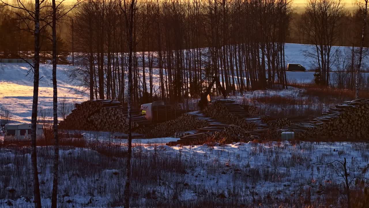 Crane loading cut logs in a snowy landscape. Aerial view