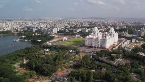 180-degree-aerial-footage-of-the-Telangana-Secretariat,-NTR-Gardens,-Hussain-Sagar-Boating-Point,-Lumbini-Park,-and-Martyrs-Memorial-situated-in-Hyderabad