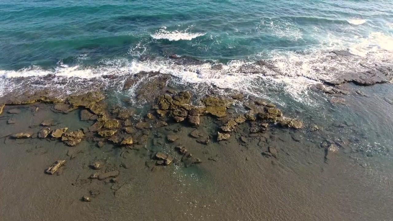 Luftfoto av havbølger som slår mot steinete strandlinje