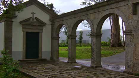 static shot of a little christian chapel in a park with some stone arches by, in porto