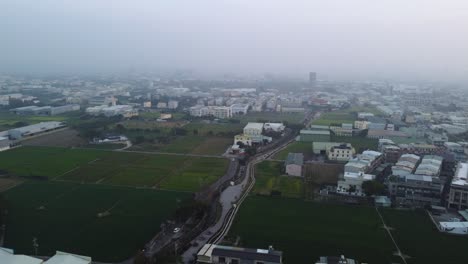 a foggy suburban landscape at dawn with houses and fields, aerial view