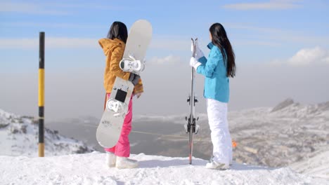 Dos-Mujeres-Practicantes-De-Snowboard-Disfrutando-De-La-Vista-Invernal.