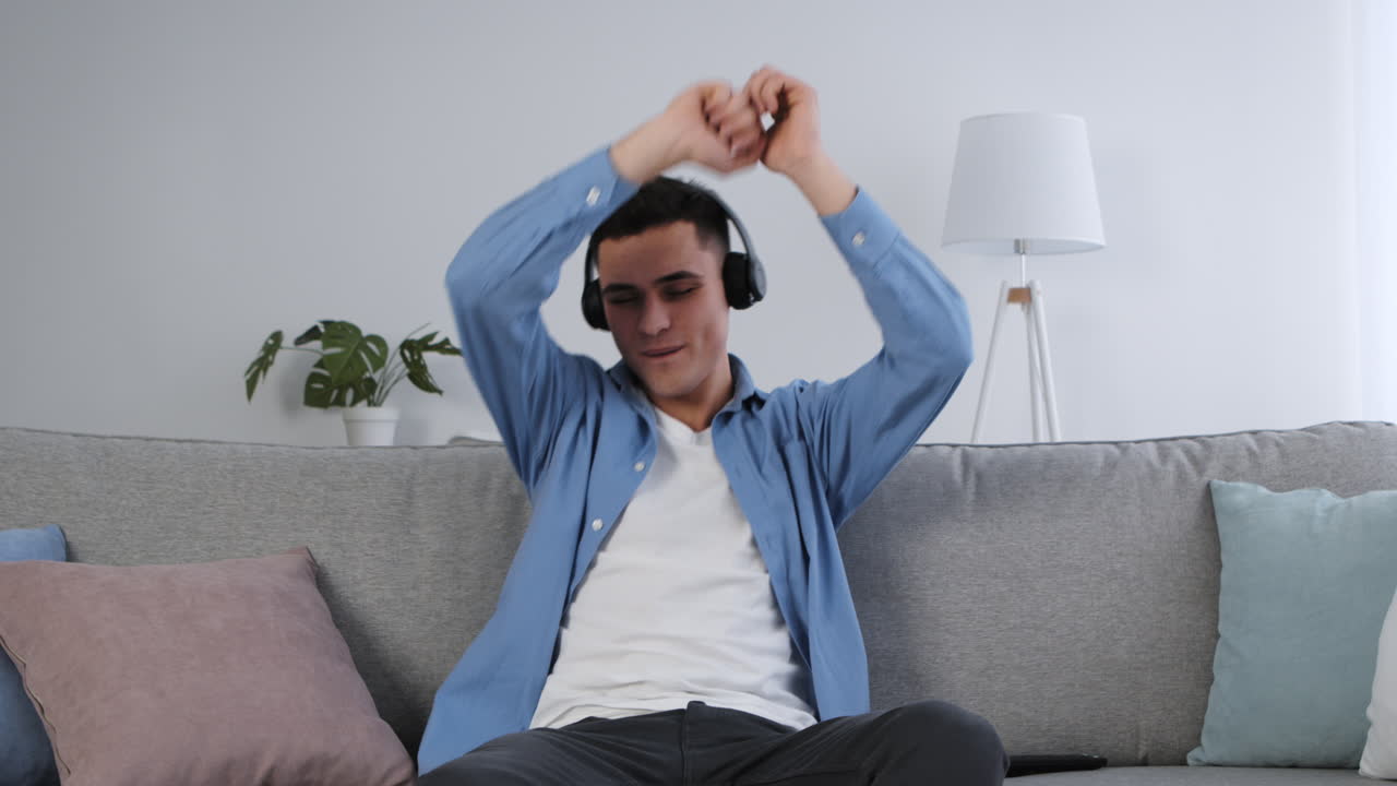 헤드폰을 들고 소파에서 춤을 추는 남자