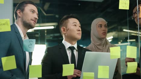 close up view of multiethnic business people group working in a modern office while writing on glass in a cabinet with sticky notes 4