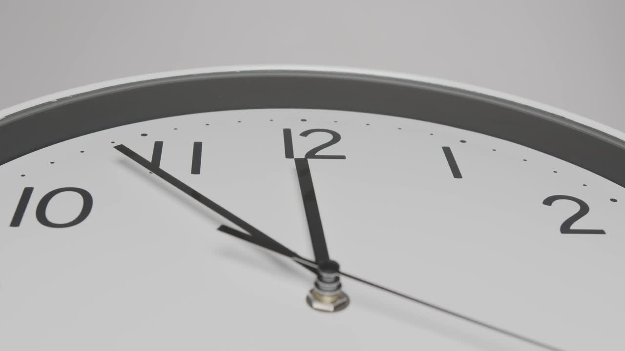 Primo piano, orologio da parete bianco, la lancetta corta indica il numero dodici