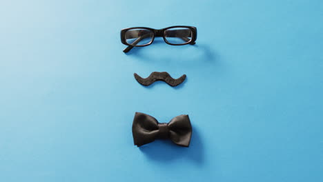video de bigote falso, gafas negras y pajarita negra sobre fondo azul con espacio para copiar.