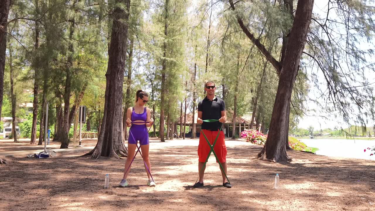 Couple exercising with resistance bands in a park