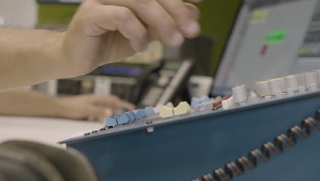 primer plano, la mano del ingeniero de audio anónimo girando la perilla en el mezclador de audio en el estudio de grabación