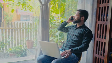 hombre trabajando desde casa en una computadora portátil y una llamada telefónica