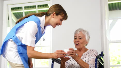 nurse giving a cup to mature woman