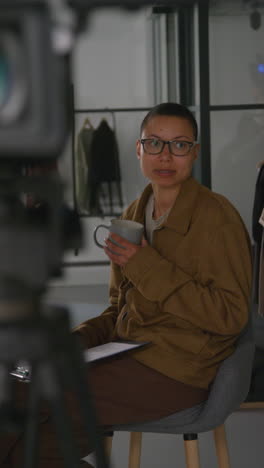 Vertical-Video-Of-Female-Film-Director-Sitting-In-Chair-Watching-Performance-Of-Actors-Shooting-Movie-In-Studio-Shot-In-Real-Time