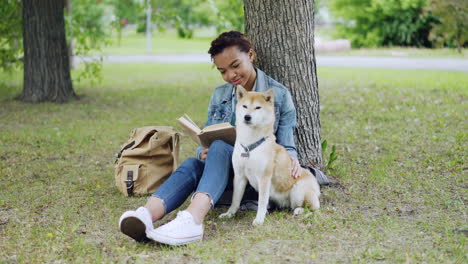teenager reading in a park with a dog