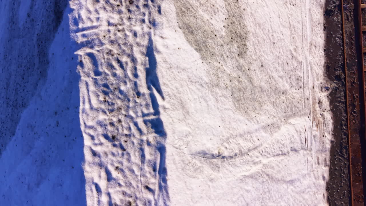 Vast white landscape transitions to earthy tones under the clear sky during the crisp morning hours