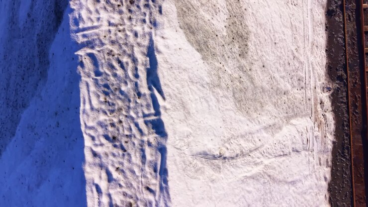 Vast white landscape transitions to earthy tones under the clear sky during the crisp morning hours