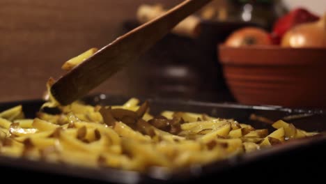 junk potato french fries being tossed in a grill container, closeup