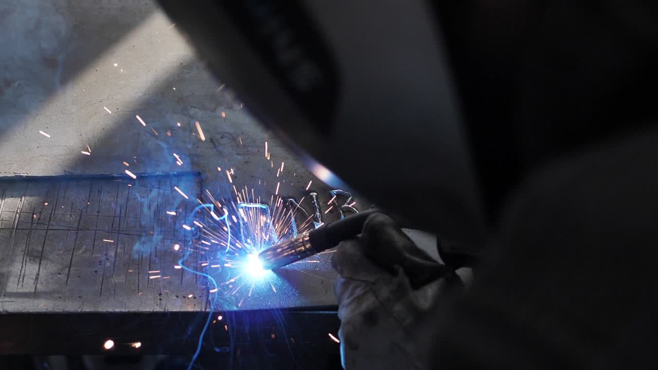 Welder on the table welds a set of metal parts