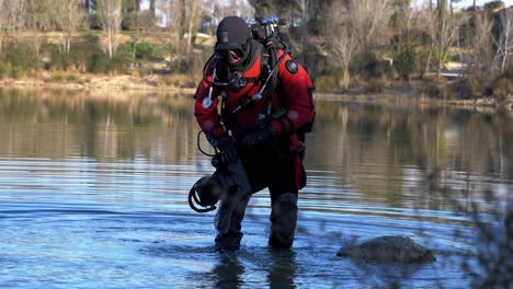 a diver grabs his flippers and enters a lake with his red buoy in the middle of winter