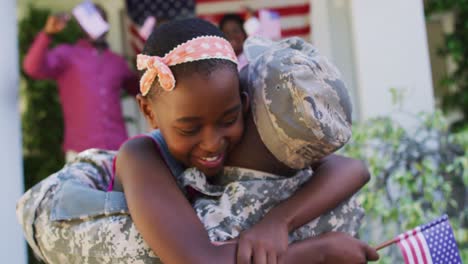 African-american-soldier-father-hugging-smiling-daughter-with-family-and-american-flag-behind