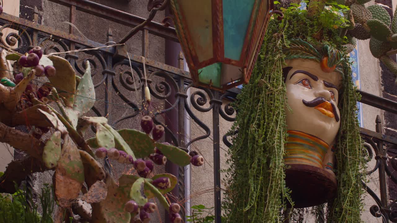 Panning shot of Sicilian Moorish Heads hanging full of plants, exuding a traditional Sicilian vibe, in Taormina, Sicily, Italy (Sicilia, Italia)