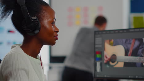 editor de video africano con auriculares escuchando música mientras edita imágenes