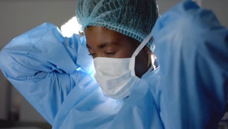 african american female surgeon wearing face mask in operating theatre, slow motion