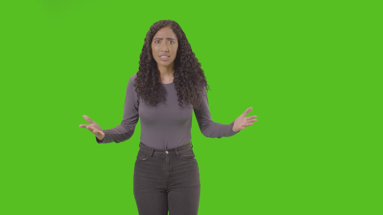 Three Quarter Length Shot Of Angry Looking Woman Shouting At Camera Against Green Screen